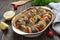 Baked fish with vegetables. Pieces of herring, onions, tomato, lemon, aromatic herbs in ceramic form on a rustic wooden table