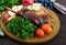 Baked goose legs, served with apples, vegetables, grapes, greens on a round oak tray