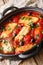 Baked Halloumi cheese with tomatoes, peppers, olives close-up in a pan. vertical
