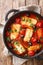 Baked Halloumi cheese with tomatoes, peppers, olives close-up in a pan. Vertical top view