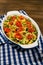 Baked homemade pasta fusilli with bacon and cream, spinach and fresh cherry tomatoes on the napkin stand on wooden table. Front