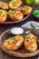 Baked loaded potato skins with cheddar cheese and bacon on wooden plate, garnished with scallions and sour cream, vertical