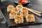 Baked Maki sushi on dark slate. Hot unagi maki with eel. Sushi roll with baked eel, cheese and unagi sauce topped. Style concept