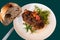 Baked meatloaf and herb twig on white plate, bread and knife on green background