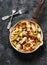 Baked mozzarella pasta with zucchini, mushrooms, sweet paprika vegetable stewed tomato sauce in a pan on a dark background, top