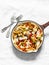 Baked mozzarella pasta with zucchini, mushrooms, sweet paprika vegetable stewed tomato sauce in a pan on a light background, top