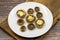 Baked mushrooms in a ceramic plate on a wooden background.