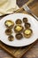 Baked mushrooms in a ceramic plate on a wooden background.