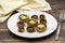 Baked mushrooms in a ceramic plate on a wooden background.