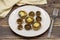 Baked mushrooms in a ceramic plate on a wooden background.