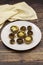 Baked mushrooms in a ceramic plate on a wooden background.