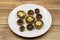 Baked mushrooms in a ceramic plate on a wooden background.