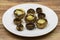 Baked mushrooms in a ceramic plate on a wooden background.