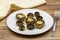 Baked mushrooms in a ceramic plate on a wooden background.