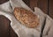 Baked oval bread made from rye flour with pumpkin seeds on a gray linen napkin