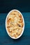 Baked panettone pudding in oval baking dish on navy blue background