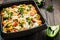 Baked pasta with broccoli and cheesy tomato sauce on wood background