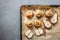 Baked pears and apples on baking pan with spices, little pumpkins and flowers around on grey table