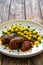 Baked pork cheeks in sauce with gnocchi and green peas on wooden table