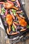 Baked pork chops with caramelized onions and rhubarb close-up in a baking sheet. Vertical top view