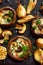 Baked portobello mushrooms stuffed with cheese and herbs on a black background, close-up.