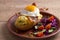 Baked potato in jacket loaded with cheese and topped with bacon and fried egg on plate with vegetables