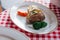 Baked potato served with grilled carrot, corn and broccoli in white plate on red and white pattern tablecloth