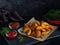 Baked potato wedges. Mexican potatoes. Dark background. On a stone board