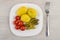 Baked potatoes with pickled tomatoes, gherkins in plate and fork