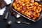 Baked potatoes with spices and tomato juice on glass baking tray