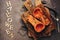 Baked pumpkin or butternut squash with herbs on a cutting board, dark rustic background. Halloween. Flat lay, top view