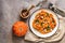 Baked pumpkin with herbs and blue cheese in a plate on a beige rustic background. Top view, flat lay, copy space