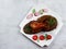 Baked quail on a square plate on a light gray background