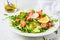 Baked red fish salad with avocado, cucumber, radish and arugula in white plate