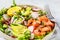 Baked red fish salad with avocado, cucumber, radish and arugula in white plate