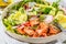 Baked red fish salad with avocado, cucumber, radish and arugula in white plate