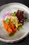 Baked root vegetables in handmade ceramic dishware. Vegan food - caramelized carrot, beetroot and celery on modern crockery.