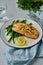 Baked salmon with asparagus, lemon slice, parsley, oil and glass of water. Healthy diet food