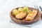 Baked salmon in creamy sauce with young boiled  potato topped with melted butter and chopped dill on  wooden plate, horizontal,