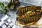 Baked salmon fish with pesto sauce and culinary spices on a gray stone countertop.