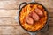 Baked Sauerkraut Podvarak with carrot, onion, smoked pork and bacon closeup in the pan. horizontal top view