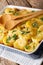 Baked sauerkraut with potatoes, bacon and cheese closeup in baking dish on the table. vertical