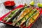 Baked saury on a red rectangular dish , close-up top view