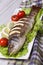 Baked sea bass with lemon, lettuce and tomatoes. vertical