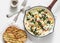 Baked shakshuka with spinach, tomatoes and mozzarella in a cast-iron pan and grilled ciabatta on a light background, top view