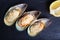 Baked shellfish mussels with slice of lemon on black stone table