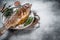 Baked silver trout, roasted fish on a plate with herbs. White background. Top view. Free space for your text