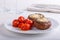 Baked stuffed champignon caps and baked cherry tomatoes on white plate. Mushrooms stuffed with vegan cashew mayonnaise. Vegetarian