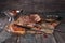 Baked succulent pork meat, sliced pieces on parchment paper, close-up with bread and tomato sauce, dark wooden rustic background