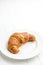 Baked tasty croissant on plate on white table